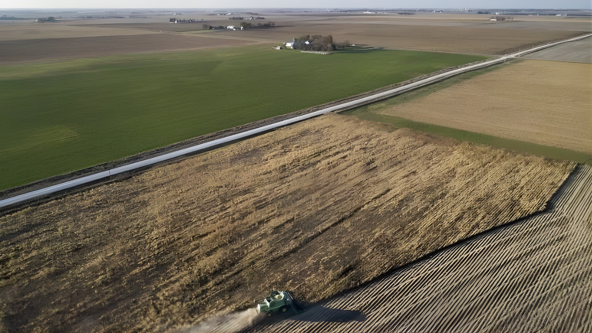Aerial view of farmland with harvested fields and machinery in operation