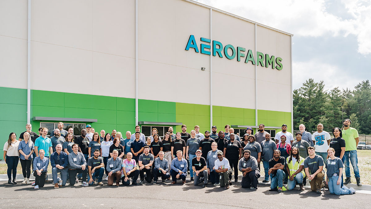 A large group of AeroFarms employees posing outside a vertical farming facility